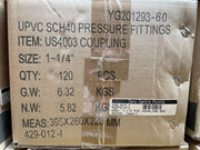 A cardboard shipping box for UPVC SCH40 pressure fittings, specifically coupling item US4003, with printed specifications, a barcode label, and metal fasteners on a brown box.