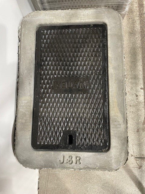 Manhole cover with 'Delphi' branding on a concrete surface