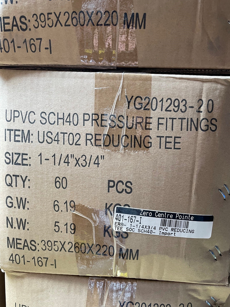 A close-up of stacked cardboard shipping boxes containing UPVC SCH40 pressure fittings, with printed product details including size, quantity, and a barcode label.