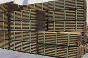 Stacked green tree stakes with visible straps, intended for use as supports for planting trees