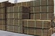 Stacked green tree stakes with visible straps, intended for use as supports for planting trees