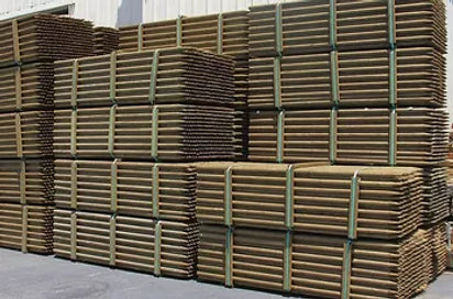Stacked green tree stakes with visible straps, intended for use as supports for planting trees