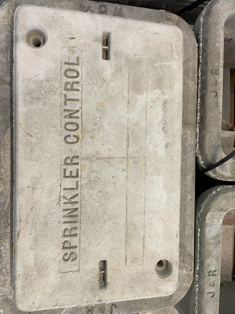 A gray concrete pull box lid with the words 'SPRINKLER CONTROL' written on it.