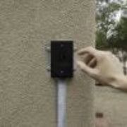 Hand pressing a button on a wall-mounted device with a clear background