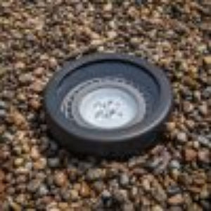 Round black object on a gravel surface