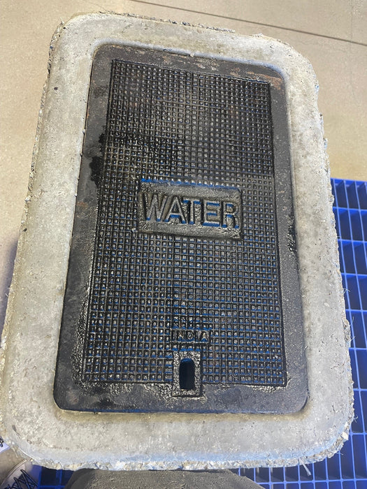 Black mat with 'WATER' text on a white foam block, on a blue grid background.