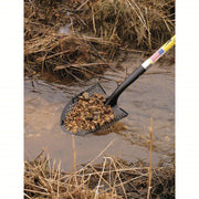 Shovel with a black handle holding rocks over water and dry grass.