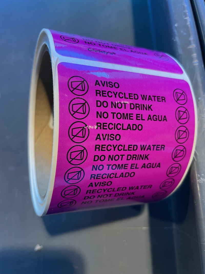 Roll of pink labels with text and icons on a reflective surface