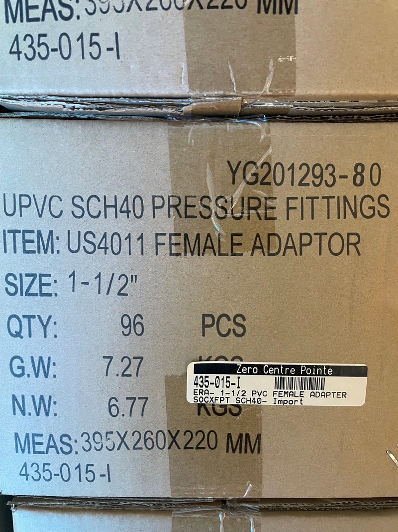 A close-up of a cardboard shipping box printed with product details for UPVC SCH40 pressure fittings, specifically a US4011 female adapter, size 1-1/2 inches.
