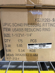 A close-up of a brown cardboard shipping box printed with product details for a US4005 reducing ring pressure fitting, including size, quantity, weight, and measurements. A barcode label is visible on the front of the box.