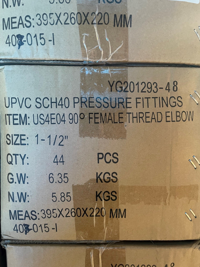 A close-up of stacked cardboard boxes containing UPVC SCH40 pressure fittings, with printed specifications including female thread elbow, size 1-1/2 inches, quantity 44 PCS, and weight details.