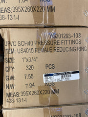 A close-up of stacked brown cardboard shipping boxes with printed product information for UPVC pressure fittings, including size, quantity, weight, and a barcode label.