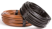 Two rolls of irrigation dripline tubing, one in brown and one in black, coiled and secured with black straps.