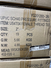 Close-up of a cardboard shipping box printed with product details for UPVC SCH40 pressure fittings, including item code US4T04 female thread tee, size 2 inch, quantity 19 pieces, and weight information.