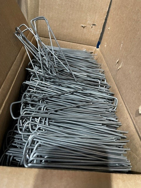 A box filled with silver sod staples with flat top design, intended for use in landscaping and irrigation.