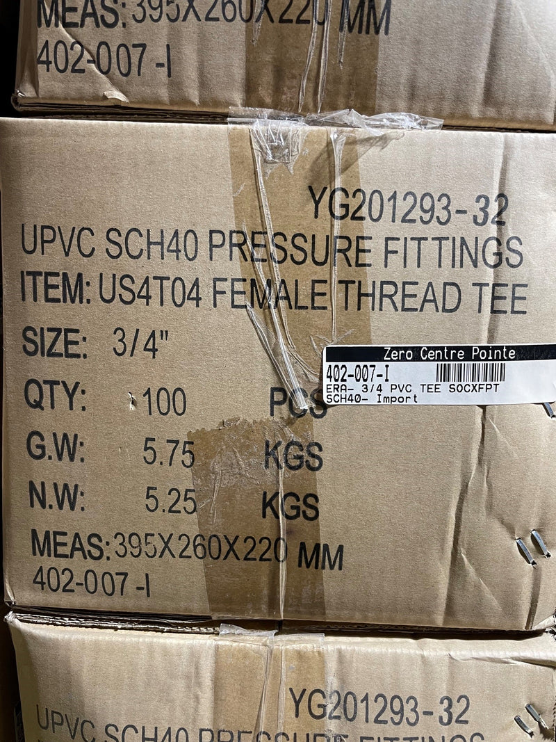 Stacked cardboard shipping boxes printed with product information for UPVC SCH40 pressure fittings, including item number US4T04 Female Thread Tee, size 3/4 inch, and weight details.