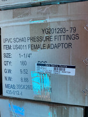 A close-up of a cardboard shipping box with printed product information for UPVC SCH40 pressure fittings, including item number US4011 female adaptor, size 1-1/4 inches, quantity 160, and weight details.