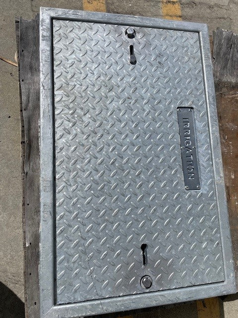 A custom galvanized metal lid for a concrete box, featuring diamond plate design with the word 'IRRIGATION' marked on it.