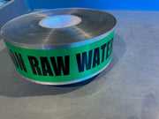 A roll of detectable green raw water marking tape with black text on it placed on a metallic surface.