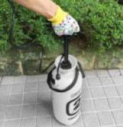 Person using a hand pump to inflate a white balloon with black text on a concrete surface.