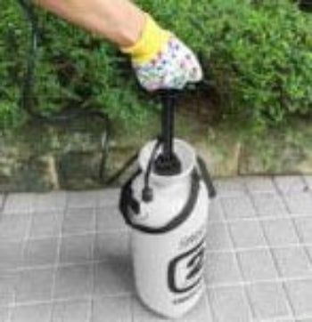 Person using a hand pump to inflate a white balloon with black text on a concrete surface.