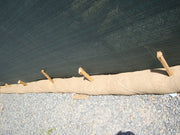 Long roll of brown paper or fabric with wooden stakes on a gravel surface.
