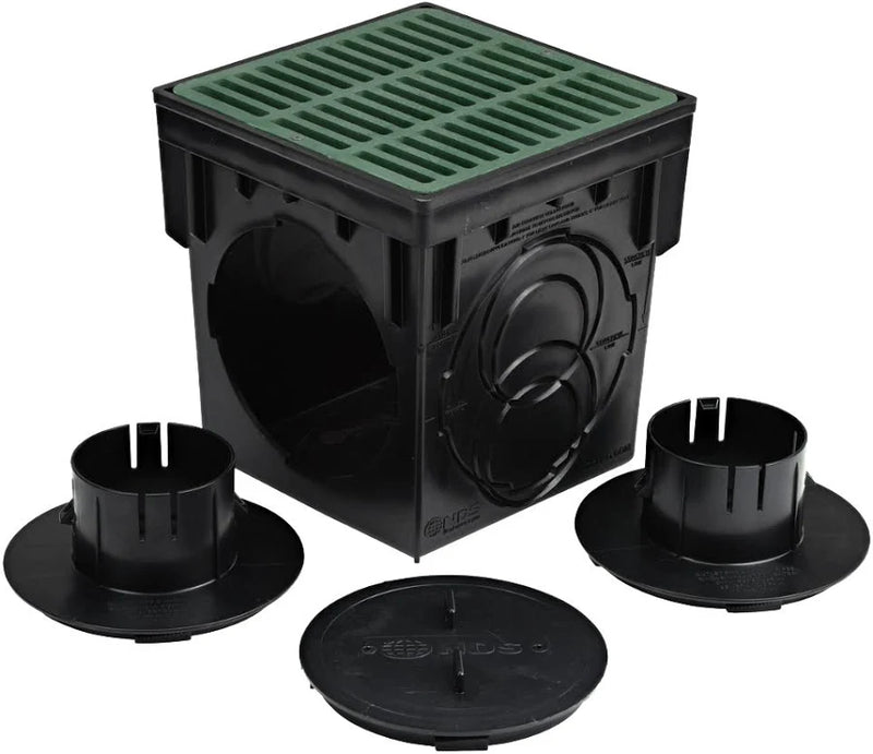 Black plastic square drainage inspection box with a green top grate, shown with two black flanges and a round access cover on a white background.