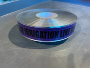 A roll of detectable purple irrigation line marking tape with the text 'IRRIGATION LINE BULK' printed on it.
