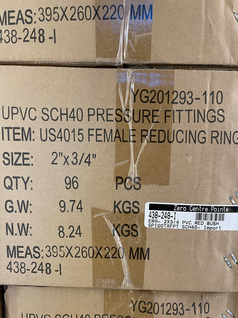 A close-up of stacked brown cardboard boxes containing UPVC SCH40 pressure fittings, with printed text including 'FEMALE REDUCING RING', size '2" x 3/4"', quantity '96 PCS', and a white barcode label reading 'Zero Centre Pointe'.