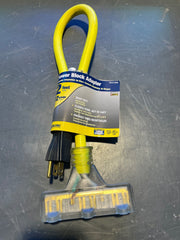 A yellow and black outdoor power block adapter with a 2-foot flexible cord and a clear plastic ground sleeve, shown with its retail paper band on a scratched dark gray metal surface.