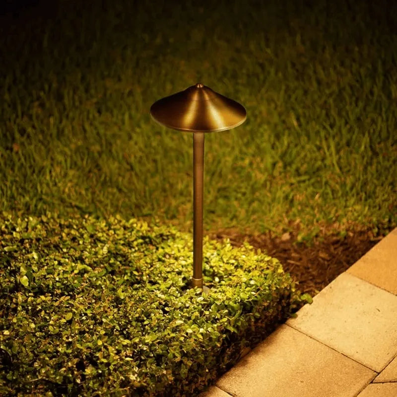 Bronze outdoor lamp post illuminating a garden path at night.