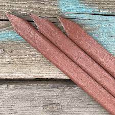 A redwood-colored plastic stake lying on a wooden surface.