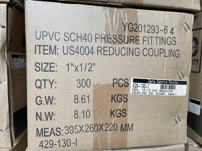 A brown cardboard shipping box printed with product details for UPVC SCH40 pressure fittings, including item number US4004 reducing coupling, size 1"x1/2", quantity 300, and weight information. A white barcode sticker is visible on the front.