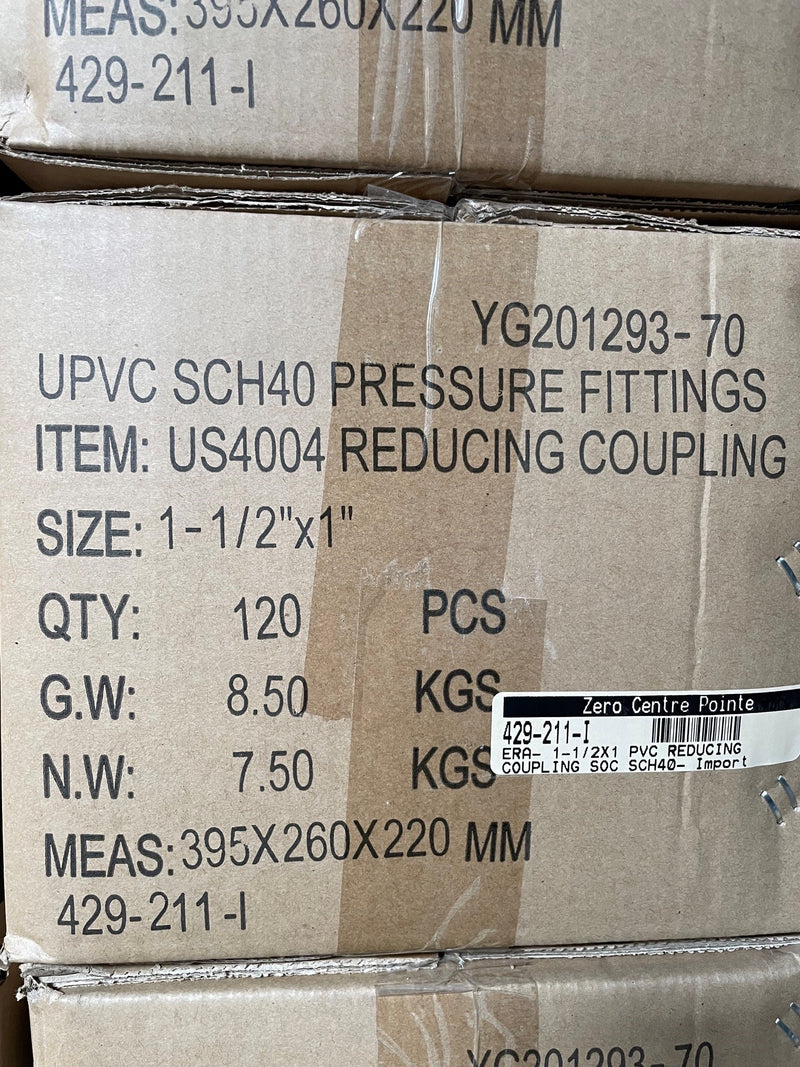 A close-up of stacked cardboard shipping boxes containing UPVC SCH40 pressure fittings. The front box is printed with product details including 'UPVC SCH40 PRESSURE FITTINGS', 'REDUCING COUPLING', size '1-1/2" x 1"', quantity '120 PCS', and weight details.