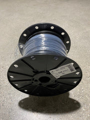 A spool of black electrical irrigation wire on a gray surface, typically used for watering systems.