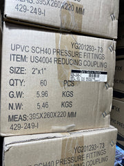 Stacked cardboard boxes of UPVC SCH40 pressure fittings, with printed specifications and a white product label on the front.