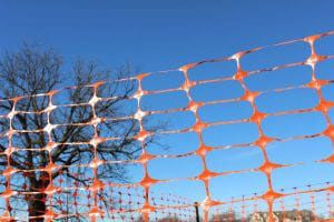 A section of orange safety fencing with diamond mesh pattern, used for crowd control and safety purposes.