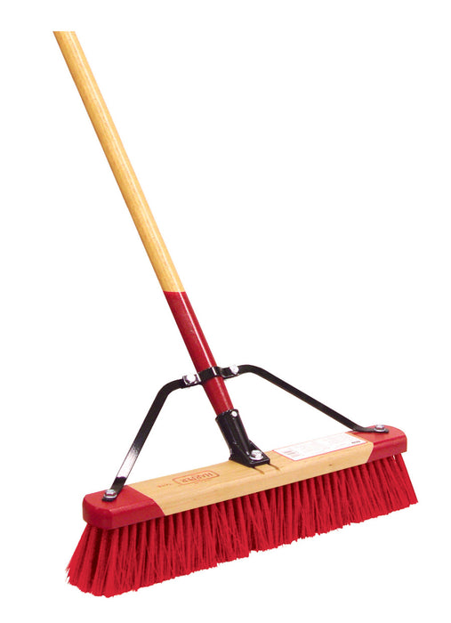 A push broom with a red and white bristle block attached to a wooden handle with a steel brace.