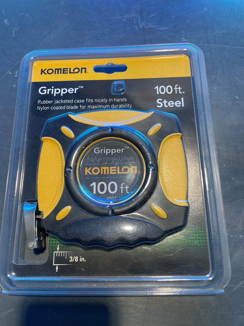Komelon Gripper 100 ft steel tape measure in its original blister pack packaging, featuring a black and yellow rubberized grip design.