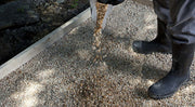 A person standing on a path made of Sakrete All Purpose 3/4" Gravel with boots raised slightly off the ground, showcasing the gravel's texture and color.
