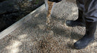 A person standing on a path made of Sakrete All Purpose 3/4" Gravel with boots raised slightly off the ground, showcasing the gravel's texture and color.