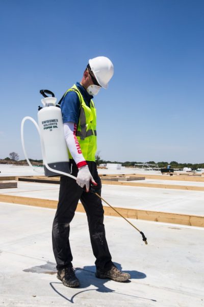 Person on a roof using a backpack sprayer