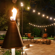 Outdoor patio with string lights, fire pit, and chairs at night.